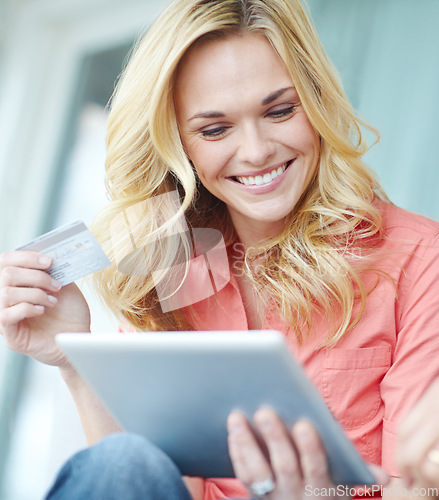 Image of Oh wow, a sale. a beautiful young woman using her digital tablet and credit card to shop online.