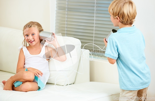 Image of I need to tell you a secret. a boy talking through a tin can connected to his sister.