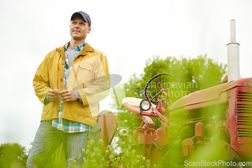 Image of Nature is my office. a farmer standing in a field with his tractor beside him - Copyspace.