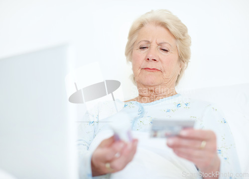 Image of Internet transactions ensure she has her medication - Senior health. Elderly hospital patient prepares to make a medicinal purchase off of the internet with her credit card.