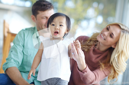 Image of You can do it. A happy couple teaching their beautiful adopted daughter to walk while at home.