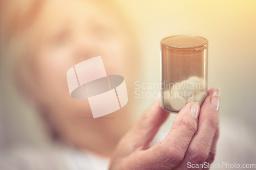 Image of Medicine to manage her chronic health condition. an elderly woman holding a container of medicine.