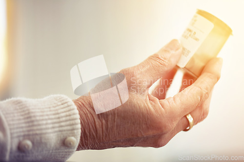 Image of Alway check the label. an elderly woman holding a container of medicine.