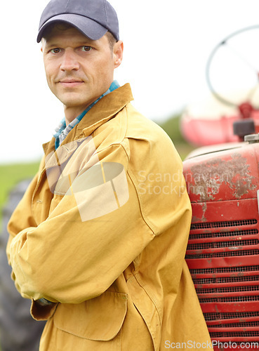 Image of I help provide your fruit and veg - Farmer. Portrait of a farmer with his arms crossed while leaning against the hood of his tractor.