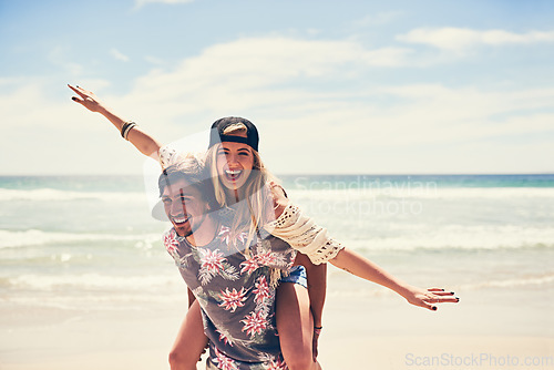 Image of He makes me feel like Im flying. Portrait of an attractive young woman getting a piggyback from her boyfriend on the beach.