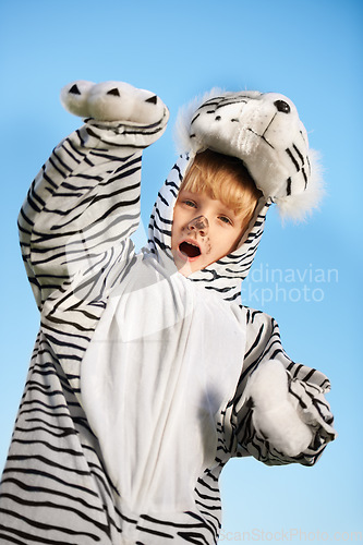 Image of Roar. Little kid wearing a tiger costumer with his arms raised while roaring.