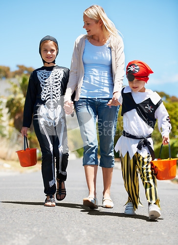 Image of Going trick or treating. Children in costume going treat or treating with their mom.