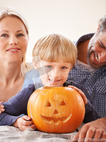 Image of Thats a good-looking jack-o-lantern. Portrait of a husband and a wife with their son behind a jack-o-lantern.