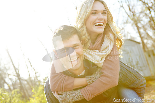 Image of This is such fun. A happy man piggybacking his girlfriend while spending time in the woods.