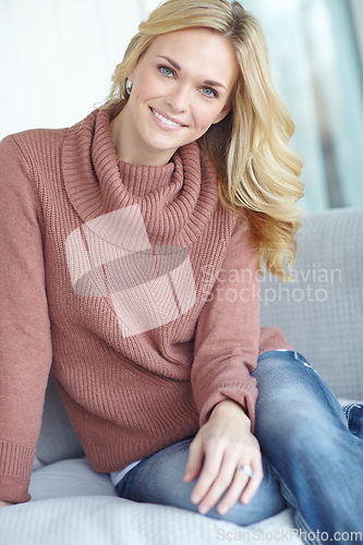 Image of Portrait of a beautiful blonde woman relaxing at home on the sofa in the lounge. Cheerful female sitting on the couch in the living room alone on the weekend. Comfy, smiling and resting inside