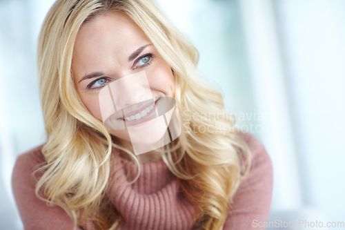 Image of Closeup of a beautiful blonde woman looking thoughtful while relaxing. Cheerful female sitting alone and thinking or daydreaming at home on the weekend. Comfy, smiling and resting inside