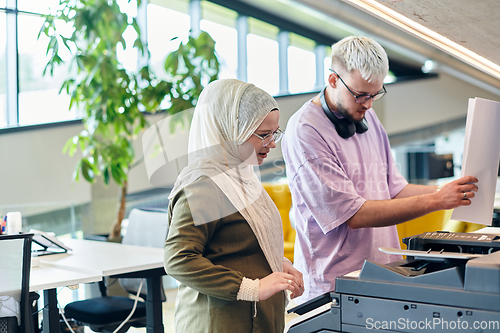 Image of In a modern startup office, a business-minded Muslim woman wearing a hijab collaborates with her colleague, symbolizing diversity, empowerment, and success in the contemporary corporate world