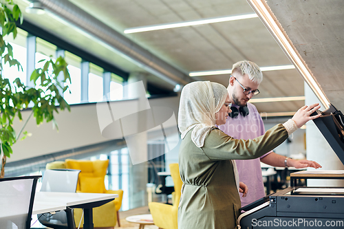 Image of In a modern startup office, a business-minded Muslim woman wearing a hijab collaborates with her colleague, symbolizing diversity, empowerment, and success in the contemporary corporate world