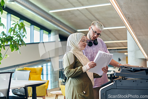 Image of In a modern startup office, a business-minded Muslim woman wearing a hijab collaborates with her colleague, symbolizing diversity, empowerment, and success in the contemporary corporate world