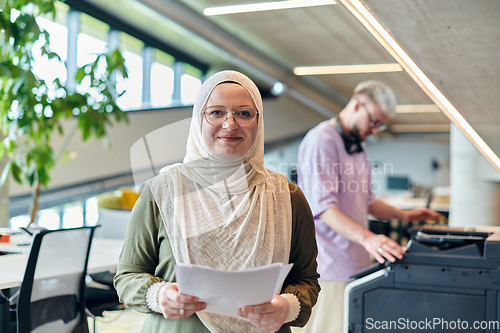 Image of In a modern startup office, a business-minded Muslim woman wearing a hijab collaborates with her colleague, symbolizing diversity, empowerment, and success in the contemporary corporate world