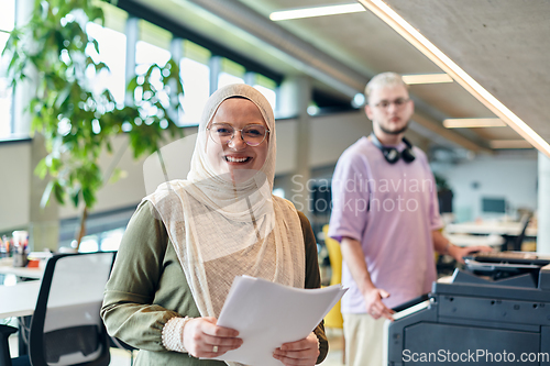 Image of In a modern startup office, a business-minded Muslim woman wearing a hijab collaborates with her colleague, symbolizing diversity, empowerment, and success in the contemporary corporate world