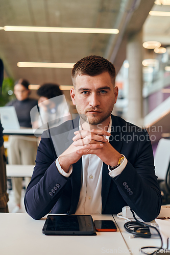Image of In a modern office setting, a determined director sits confidently at his desk with crossed arms, exemplifying professionalism, leadership, and unwavering resolve in the contemporary corporate world