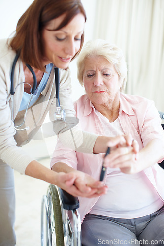 Image of Knowledge is empowering - Senior Care. A caring nurse helps an elderly female patient check her blood sugar levels herself.