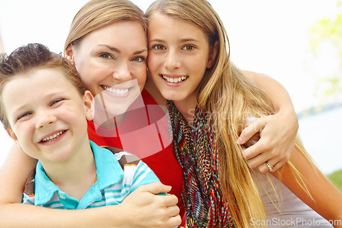 Image of Spending time with mom. Smiling mother embracing her teen daughter and young son while outdoors.