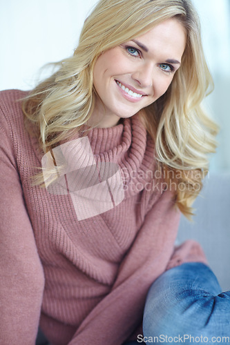 Image of Portrait of a beautiful blonde woman relaxing at home on the sofa in the lounge. Cheerful female sitting on the couch in the living room alone on the weekend. Comfy, smiling and resting inside