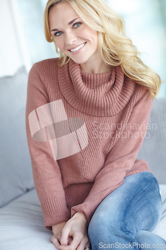 Image of Portrait of a beautiful blonde woman relaxing at home on the sofa in the lounge. Cheerful female sitting on the couch in the living room alone on the weekend. Comfy, smiling and resting inside