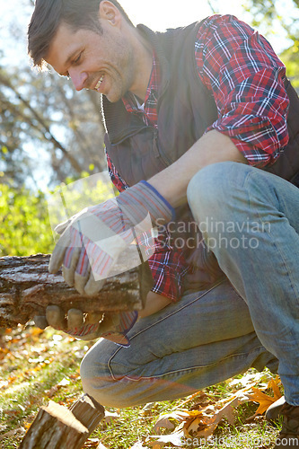 Image of Closeup of a handsome lumberjack holding a pile of wood he has collected. One mature man in the forest collecting wood for a campfire. Caucasian woodcutter in plaid shirt, looking in contemplation