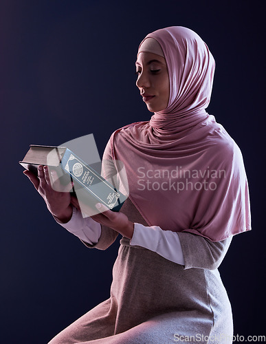 Image of Quran, faith and muslim woman reading in a studio with traditional clothes and hijab. Serious, religion and young islamic female person studying the holy Arabic book isolated by a black background.