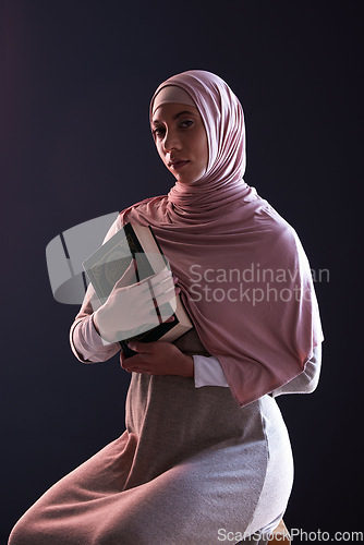 Image of Quran, religion and portrait of a muslim woman in a studio with traditional clothes and hijab. Serious, faith and young islamic female person with the holy Arabic book isolated by a black background.