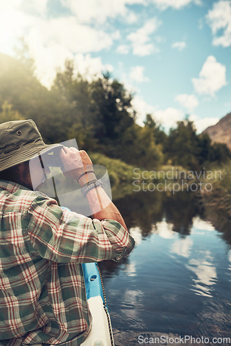 Image of Hes always searching for a new adventure. Rearview shot of a young man looking through his binoculars while enjoying a canoe ride on the lake.