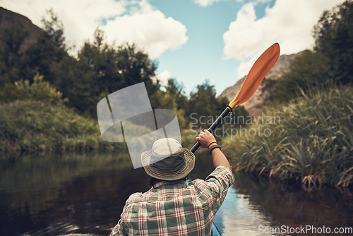 Image of Paddling towards a new adventure. Rearview shot of a young man going for a canoe ride on the lake.