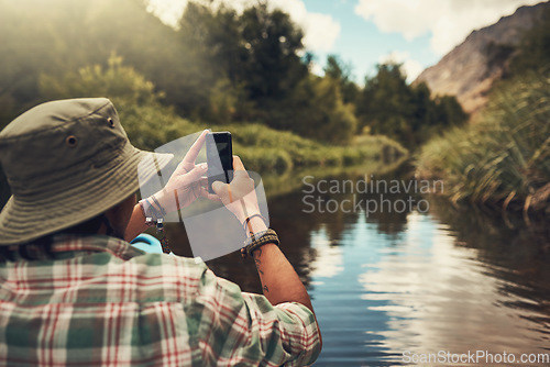 Image of Scenic snapshots are essential. Rearview shot of a young man taking photos on his cellphone while enjoying a canoe ride on the lake.