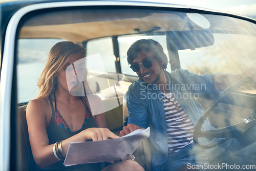 Image of Lead the way. an affectionate young couple looking at a map during their roadtrip.