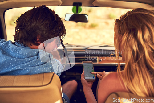 Image of Looks like were headed in the right direction. Rearview shot of an affectionate young couple following their gps during a roadtrip.