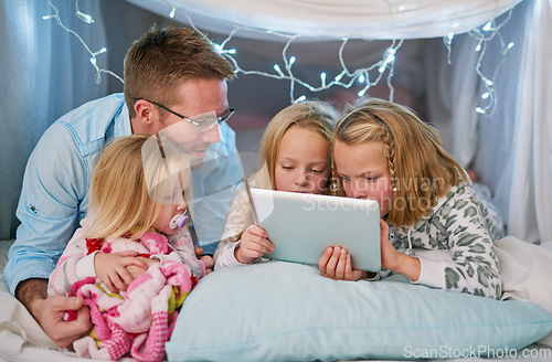 Image of Hes there to ensure safe online browsing. a father and his daughters using a digital tablet before bedtime.