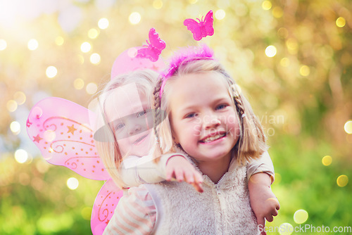 Image of This little fairy just needs some help practising to fly. Portrait of two little sisters dressed up as fairies and having fun outside.