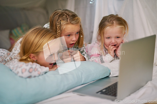 Image of Its their favourite cartoon to watch before bed. three little sisters watching something on a laptop before bedtime.