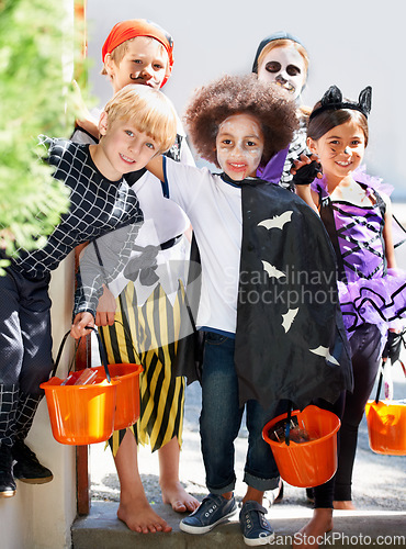 Image of Our pales are full of candy. Portrait of a group of little children trick-or-treating on halloween.