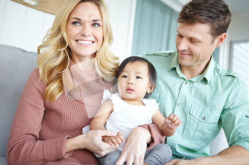 Image of Proud parents. A happy couple spending time with their beautiful adopted daughter while at home.