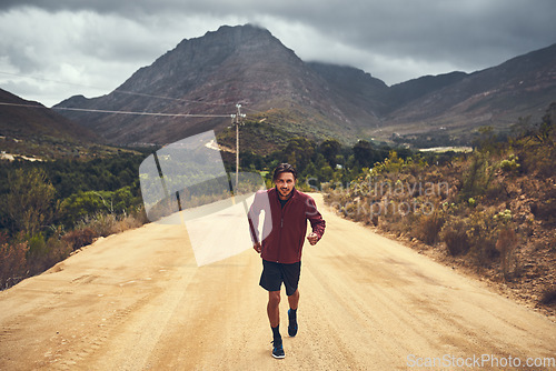 Image of Clocking some fitness hours along the scenic route. Portrait of a young man out for a trail run.