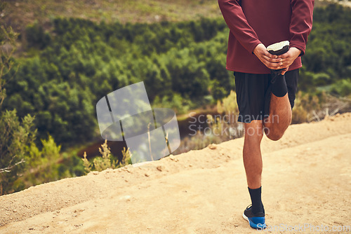 Image of Preparing his legs for a workout. Rearview shot of a young man warming up before a trail run.