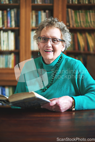 Image of Keeping my mind sharp and enjoying every page of it. Portrait of a smiling senior woman sitting at a table reading.