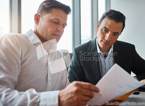 Image of Working together makes everything easier. two mature businessmen discussing paperwork in a corporate office.