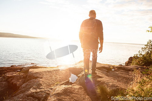 Image of The physical benefits of hiking is numerous. a man wearing his backpack while out for a hike on a coastal trail.