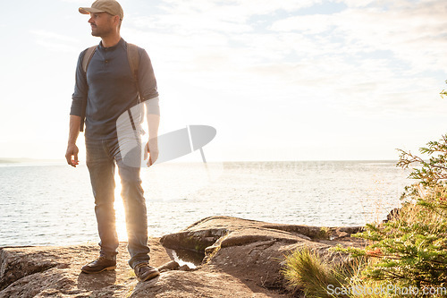 Image of I love hiking because it brings me back to simplicity. a man wearing his backpack while out for a hike on a coastal trail.