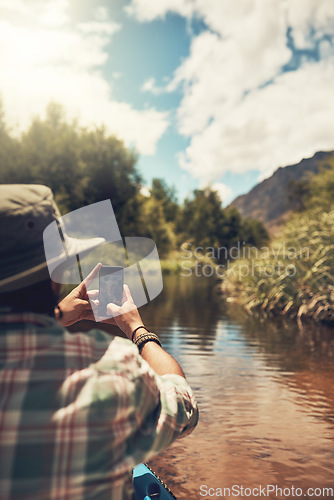 Image of Itll be an adventure to remember. Rearview shot of a young man taking photos on his cellphone while enjoying a canoe ride on the lake.