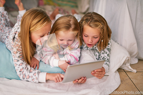 Image of Bedtime just got a whole lot more interactive. three little sisters using a digital tablet before bedtime.