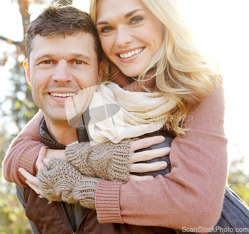Image of Love in the Fall. A happy man piggybacking his girlfriend while spending time in the woods.