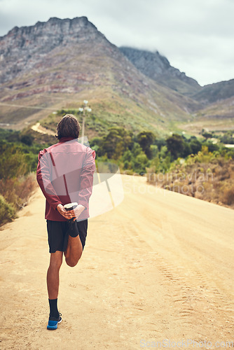 Image of The best runs are those with spectacular views. Rearview shot of a young man warming up before a trail run.