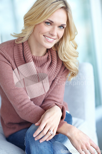 Image of Portrait of a beautiful blonde woman relaxing at home on the sofa in the lounge. Cheerful female sitting on the couch in the living room alone on the weekend. Comfy, smiling and resting inside