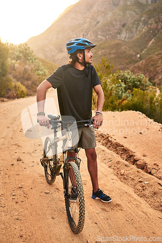 Image of Its about conquering yourself first beyond the mountain. a young man looking thoughtful while standing with his bike on a trail.